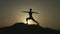 Silhouette of woman keeping balance in yoga position on mountain in sunset rays