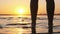 Silhouette of Woman Legs Standing in Water at Sunset on Beach. Slow Motion