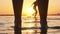 Silhouette of Woman Legs Standing in Water at Sunset on Beach. Slow Motion