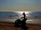 Silhouette of a woman with long blond hair sitting on a quad bike, sunny day at the beach
