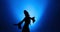 Silhouette of woman with long hair dancing in blue light and smoke