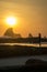 Silhouette of a woman is looking into the sunset at the beach. With reflections and birds in the sky.