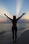 Silhouette Of Woman With Outstretched Arms On Beach