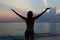 Silhouette Of Woman With Outstretched Arms On Beach