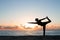 Silhouette of woman practicing authentic yoga on the beach at sunset