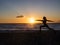 Silhouette woman practicing yoga or stretching on the beach pier at sunset or sunrise. Yoga practice, meditation and