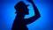 Silhouette of woman put on hat on head. Female`s face in profile with headdress on blue background
