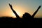 Silhouette of woman raising arms towards the sunset