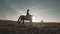 Silhouette of woman riding horse in field. Beautiful cowgirl at brown horse