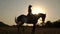 Silhouette of a woman riding a horse at sunset.