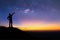 Silhouette of woman is standing on top of mountain and pointing to the milky way