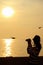 Silhouette of a woman taking pictures of flying seagulls during the sun rising on golden sky over the Gulf of Thailand