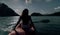 Silhouette of woman tourist raising hands while sailing in canoe along sea bay water to distant hilly island backside