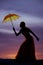 Silhouette of woman with umbrella in sunset bend