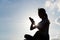 Silhouette of woman using cellphone under skyline in the evening