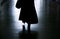 Silhouette of a woman walking away in dark alley