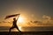 Silhouette of woman with waving flag in hand by the sea at sunset.