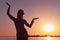 silhouette of woman woman illuminated with sunshine dancing traditional tribal belly dance in front of aurora sky at sunrise