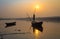 Silhouette wooden boat with oarsman at sunset on river Damodar.