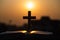 Silhouette of wooden Christian cross on bible with a bright sunrise as background , god