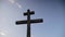 Silhouette of wooden cross on blue sky background. Close up shot from steadicam. Symbol of Christianity religion