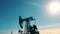 Silhouette of a working oil pumpjack in an oil field