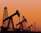 Silhouette of working oil pumps on sunset background.