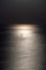 Silhouette of the yacht or leisure boat sailing toward the moon. Dark sky and Moonwalk. Reflection in water. Beautiful seascape in