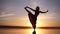 Silhouette yoga woman practicing yoga posture on sea coast at beautiful sunset. Stunning view of a woman in yogi pants