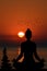 Silhouette of yogi in lotus position and a pile of stone at sea shore