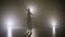 Silhouette of young ballerina dressed in white wearing pointe shoes dancing and practicing pirouettes on stage late at night -