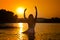 Silhouette of young beautiful woman in the river over sunset sky. Female perfect body contour at beach in twilight scenery