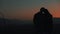 Silhouette of young couple in love enjoying a sunset over the mountains. Vacation, travel, romance, marriage proposal