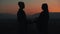 Silhouette of young couple in love enjoying a sunset over the mountains. Vacation, travel, romance, marriage proposal