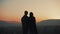 Silhouette of young couple in love enjoying a sunset over the mountains. Vacation, travel, romance, marriage proposal
