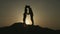 Silhouette of young couple in love hugging, kissing in sunset rays on mountain