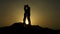 Silhouette of young couple in love hugging, kissing in sunset rays on mountain