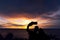 A silhouette of a young couple taking a picture with the sunset at Noen Nang Phaya viewpoint in Chanthaburi, Thailand