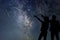 Silhouette of young couple watching Meteor Shower. Nigh Sky.