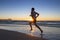 Silhouette young dynamic athlete runner man with fit strong body training on Summer sunset beach running barefoot in sport healthy