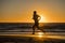 Silhouette young dynamic athlete runner man with fit strong body training on Summer sunset beach running barefoot in sport healthy