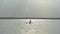 Silhouette of young female paddle boarding at sunset.