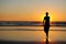 Silhouette of young girl on the background of sunset by the sea. Figure of a woman in the rays of setting sun. Beautiful sunset,