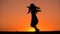 Silhouette of young girl dancing at sunset