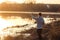 Silhouette of a young girl fishing at sunset near the lake