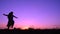Silhouette of young girl jumping at pink sunset