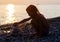 Silhouette of young girl puts pyramid from stones