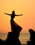 A silhouette of a young girl on rock at sunset 3