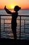 Silhouette of a young girl at sunset. Twilight, waves. Girl maki