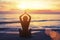 Silhouette of young girl in yoga pose sitting on the beach